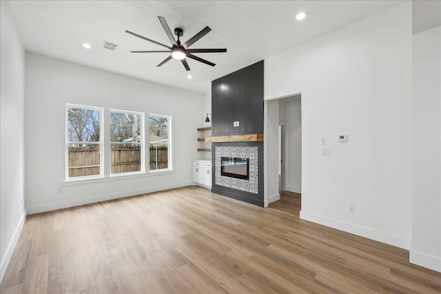 unfurnished living room with light wood finished floors, visible vents, recessed lighting, a fireplace, and a ceiling fan