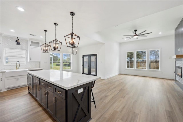 kitchen featuring tasteful backsplash, a glass covered fireplace, white cabinetry, and a sink