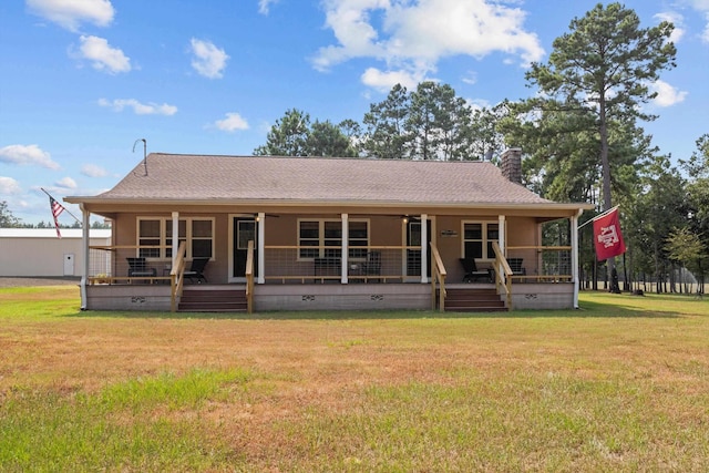 back of property with covered porch and a yard