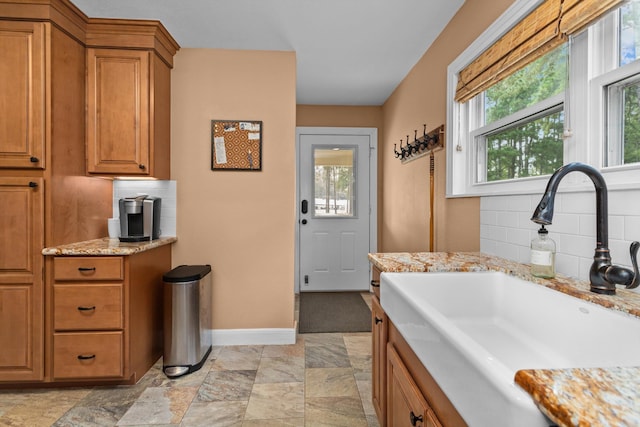 kitchen featuring decorative backsplash, sink, and light stone countertops