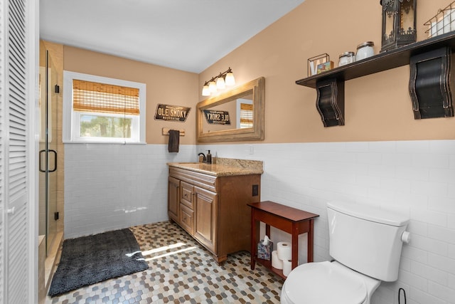 bathroom featuring tile patterned flooring, vanity, tile walls, toilet, and walk in shower