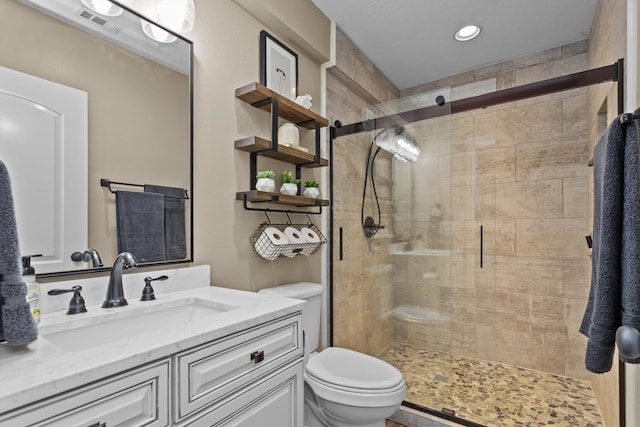 bathroom featuring vanity, a shower with shower door, and toilet