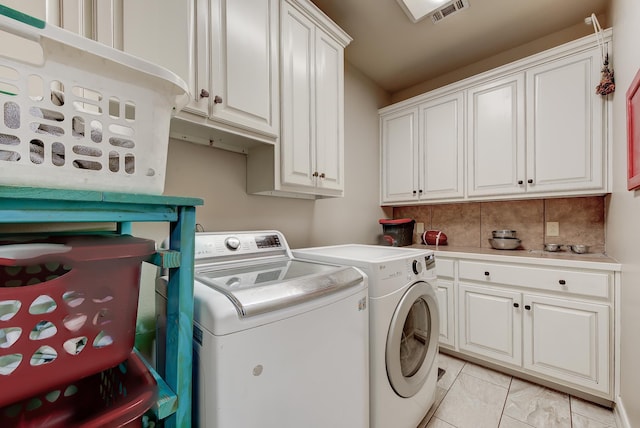 laundry room featuring washer and clothes dryer, light tile patterned flooring, and cabinets