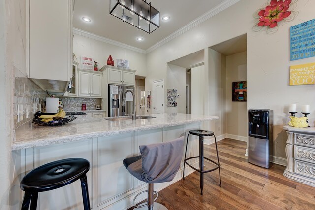 kitchen with backsplash, sink, light stone countertops, kitchen peninsula, and a breakfast bar area