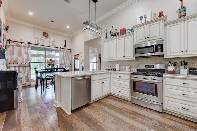 kitchen with kitchen peninsula, appliances with stainless steel finishes, hanging light fixtures, and a healthy amount of sunlight