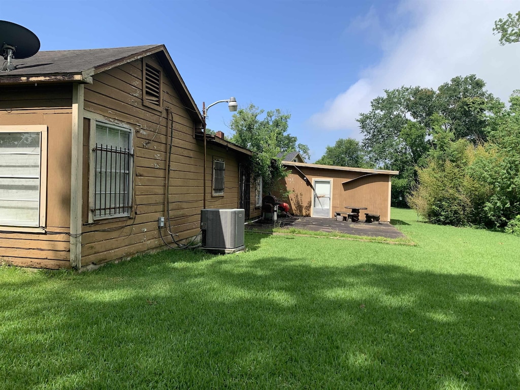 2180 Tyler St, Beaumont, TX 77703 - view of green lawn with central air condition unit and a patio area