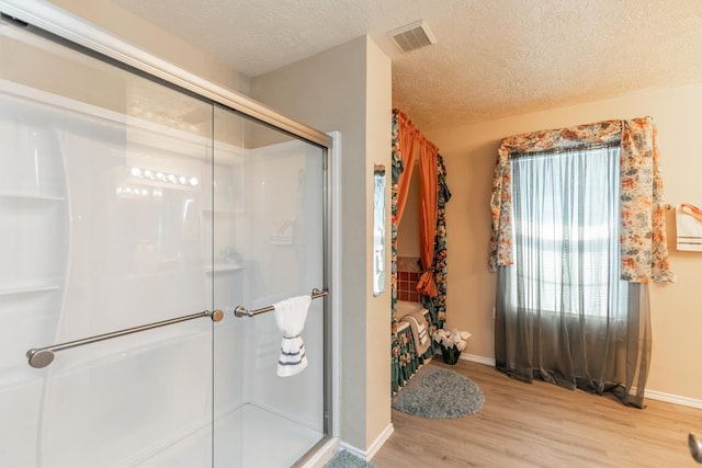 bathroom featuring hardwood / wood-style flooring, a shower with door, and a textured ceiling