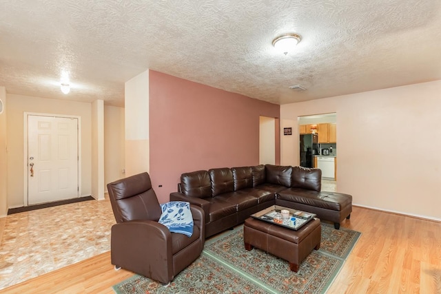 living room with a textured ceiling and light wood-type flooring