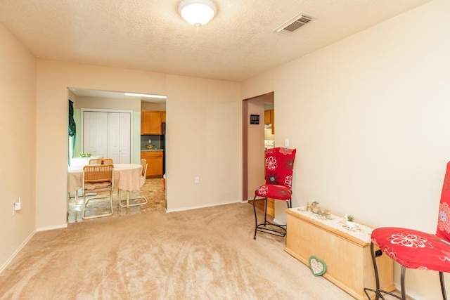 living area with light carpet and a textured ceiling