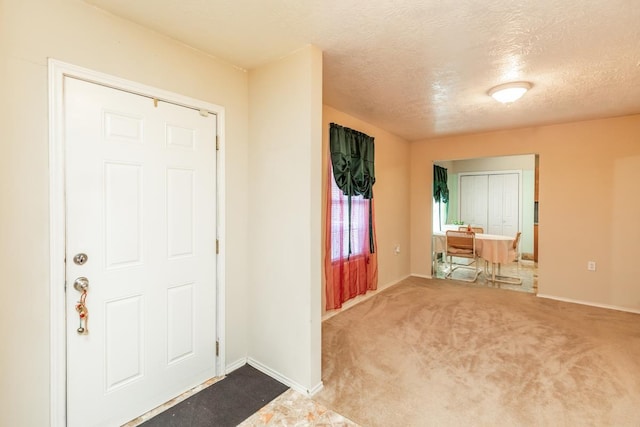 foyer entrance with carpet flooring and a textured ceiling