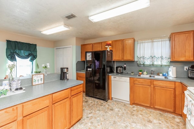 kitchen featuring sink, black fridge, white dishwasher, a textured ceiling, and range