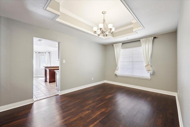 unfurnished room featuring ornamental molding, hardwood / wood-style floors, a notable chandelier, and a tray ceiling