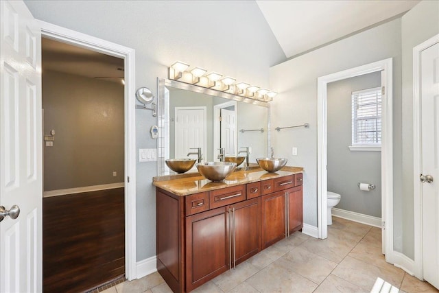 bathroom featuring vanity, vaulted ceiling, tile patterned floors, and toilet