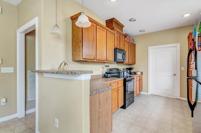 kitchen featuring light stone counters, hanging light fixtures, and black appliances