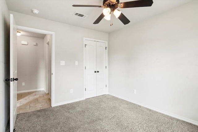 unfurnished bedroom with a closet, light colored carpet, and ceiling fan