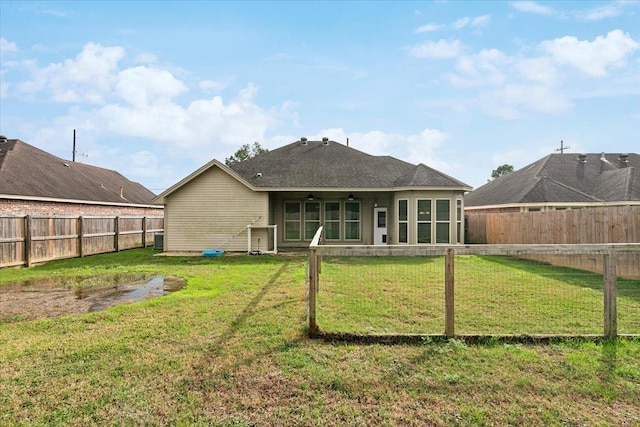 back of property with central AC unit, ceiling fan, and a yard