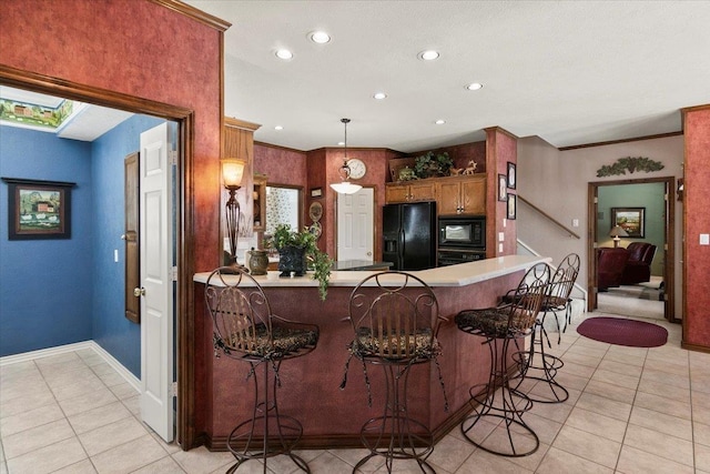 kitchen with a breakfast bar, black appliances, crown molding, hanging light fixtures, and kitchen peninsula