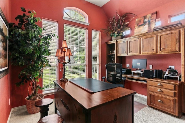 carpeted home office with vaulted ceiling