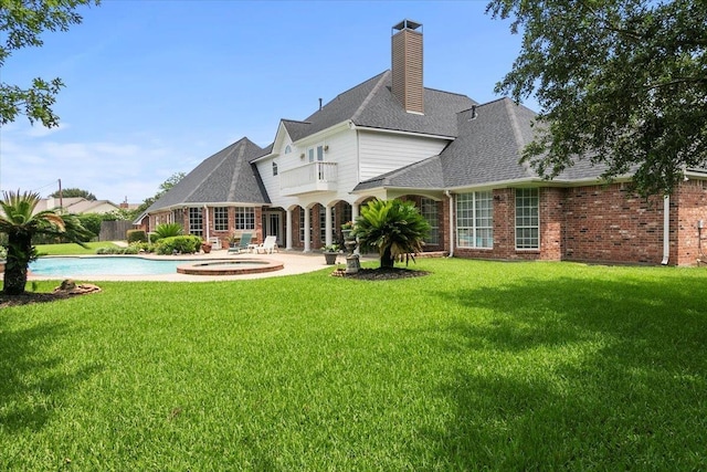 back of house with a yard, a patio area, a swimming pool with hot tub, and a balcony