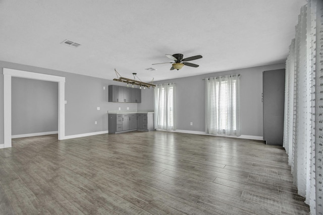 unfurnished living room with a textured ceiling, ceiling fan, and dark wood-type flooring