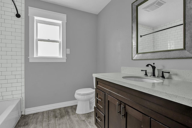 full bathroom with hardwood / wood-style floors, vanity, toilet, and tiled shower / bath