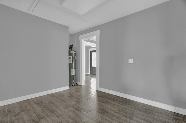 empty room featuring dark wood-type flooring and water heater