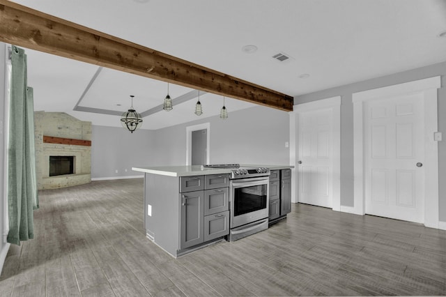 kitchen featuring gray cabinetry, stainless steel electric stove, pendant lighting, light hardwood / wood-style flooring, and a fireplace