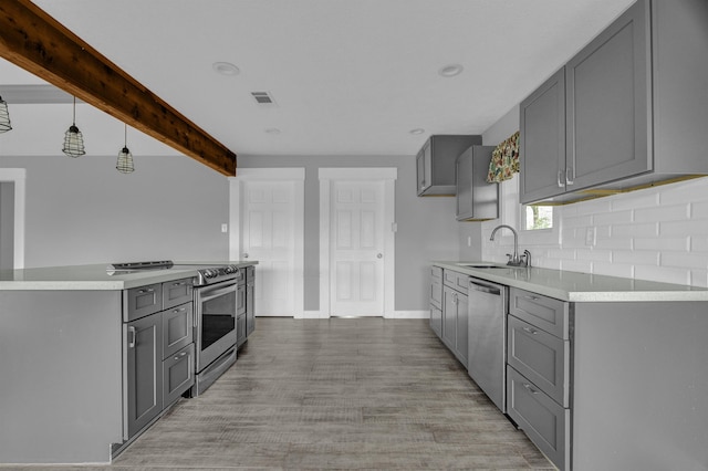 kitchen featuring beamed ceiling, gray cabinetry, light wood-type flooring, and appliances with stainless steel finishes