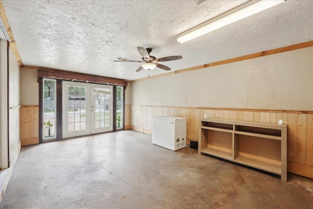 275 E Clover Ln, Bridge City, TX 77611 - spare room with unfinished concrete flooring, ceiling fan, a wainscoted wall, wood walls, and a textured ceiling