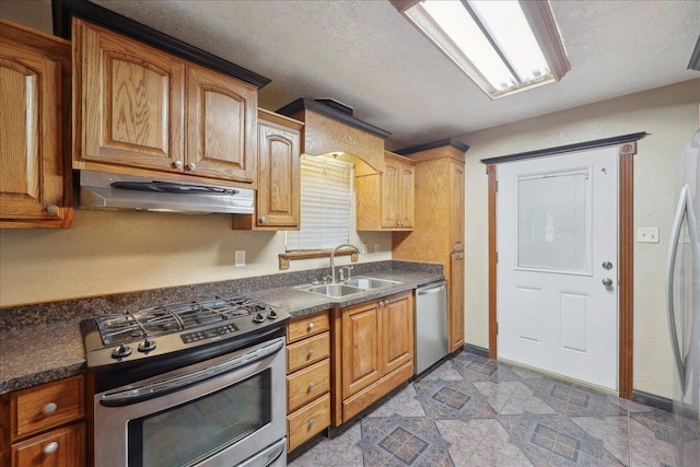 275 E Clover Ln, Bridge City, TX 77611 - kitchen with appliances with stainless steel finishes, under cabinet range hood, a sink, dark countertops, and a textured ceiling