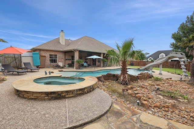 640 Winchester Dr, Bridge City, TX 77611 - view of swimming pool with a water slide, a patio, a fenced backyard, and a pool with connected hot tub