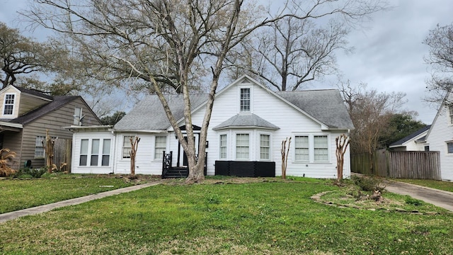 bungalow-style house featuring a front yard, fence, and roof with shingles