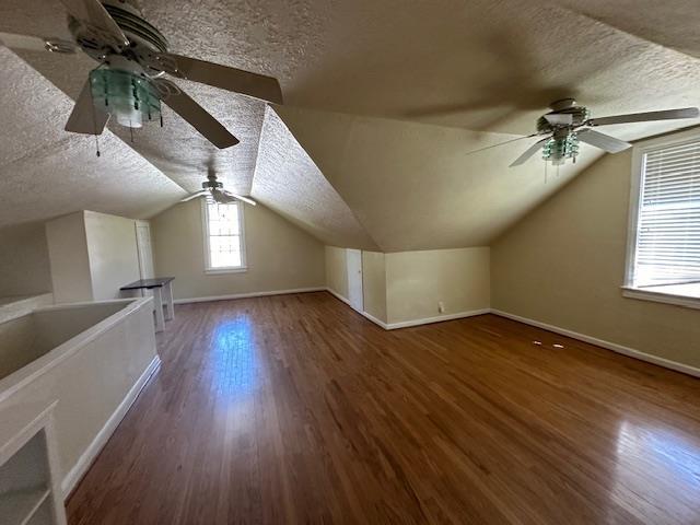 additional living space with lofted ceiling, a textured ceiling, and dark wood-type flooring