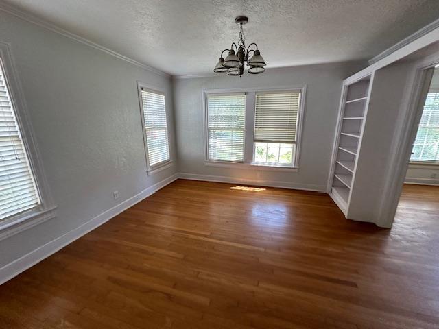 unfurnished dining area featuring a healthy amount of sunlight, a textured ceiling, dark wood-type flooring, and a notable chandelier