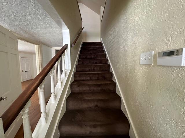 stairs featuring a textured ceiling