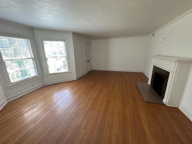 unfurnished living room with dark hardwood / wood-style flooring, a textured ceiling, and ornamental molding