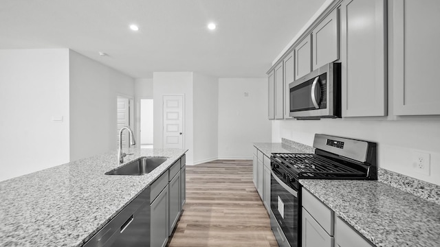 kitchen featuring light stone countertops, appliances with stainless steel finishes, gray cabinetry, and sink