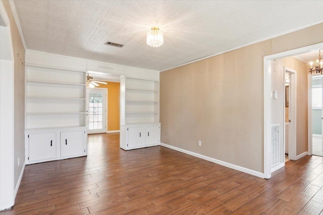 spare room featuring ceiling fan with notable chandelier, dark hardwood / wood-style flooring, built in features, and ornamental molding