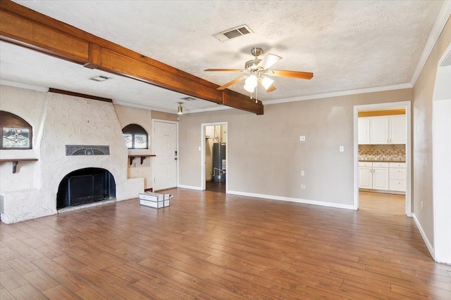 unfurnished living room with ceiling fan, beamed ceiling, hardwood / wood-style floors, a textured ceiling, and a fireplace