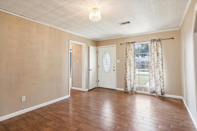 entrance foyer featuring wood-type flooring, ornamental molding, and an inviting chandelier