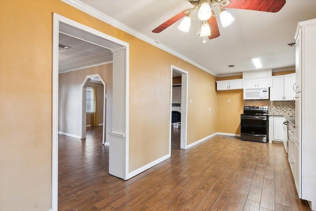 kitchen featuring tasteful backsplash, stainless steel appliances, crown molding, hardwood / wood-style flooring, and white cabinetry