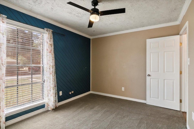 empty room with ceiling fan, ornamental molding, a textured ceiling, and dark colored carpet