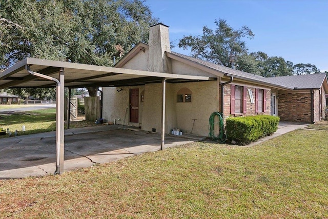 exterior space with a carport and a lawn