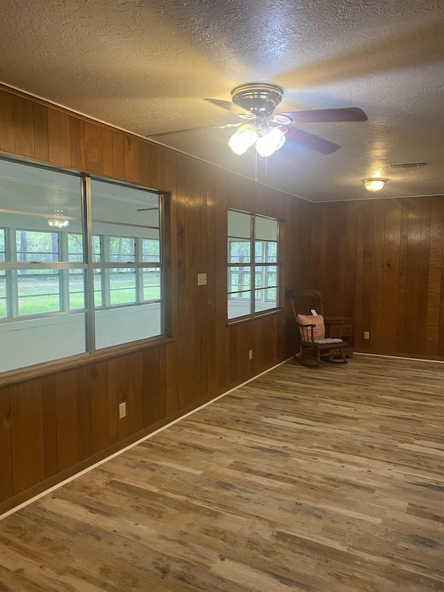 unfurnished room featuring visible vents, wood finished floors, ceiling fan, and a textured ceiling