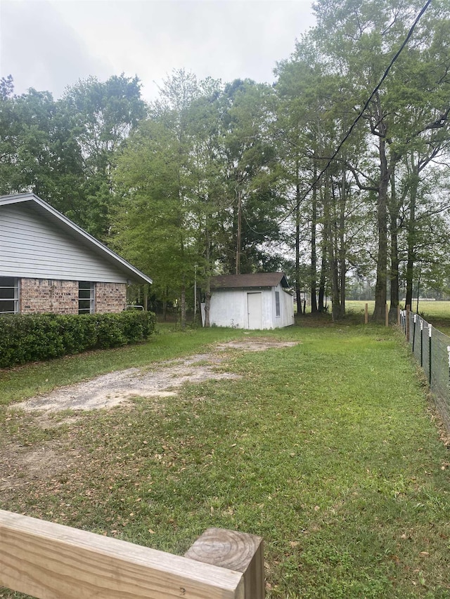 view of yard featuring an outbuilding, fence, and a storage shed