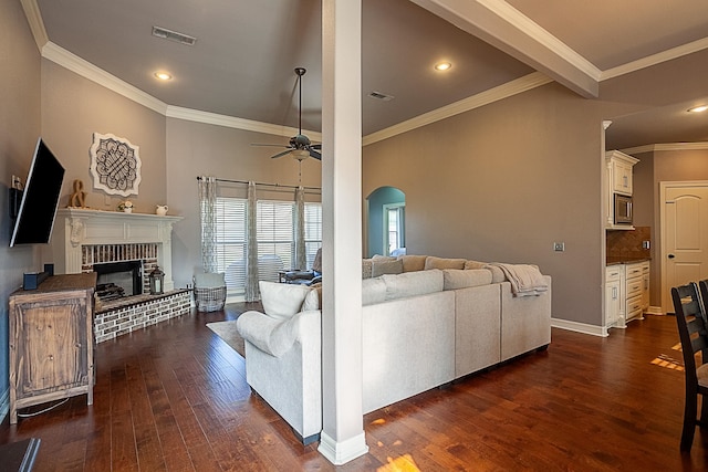 living room with ceiling fan, a fireplace, dark wood-type flooring, and ornamental molding