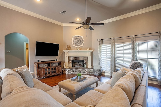 living room with a brick fireplace, ceiling fan, dark hardwood / wood-style flooring, and ornamental molding