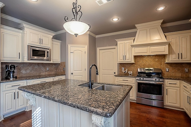 kitchen featuring custom exhaust hood, a center island with sink, sink, appliances with stainless steel finishes, and tasteful backsplash