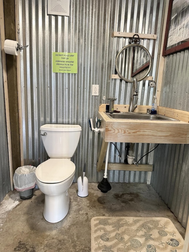 half bathroom with a sink, toilet, and unfinished concrete floors