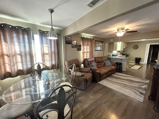 dining room with ceiling fan, a textured ceiling, wood finished floors, visible vents, and baseboards